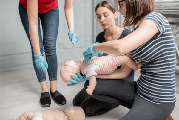 Baby doll with 3 adults performing first aid